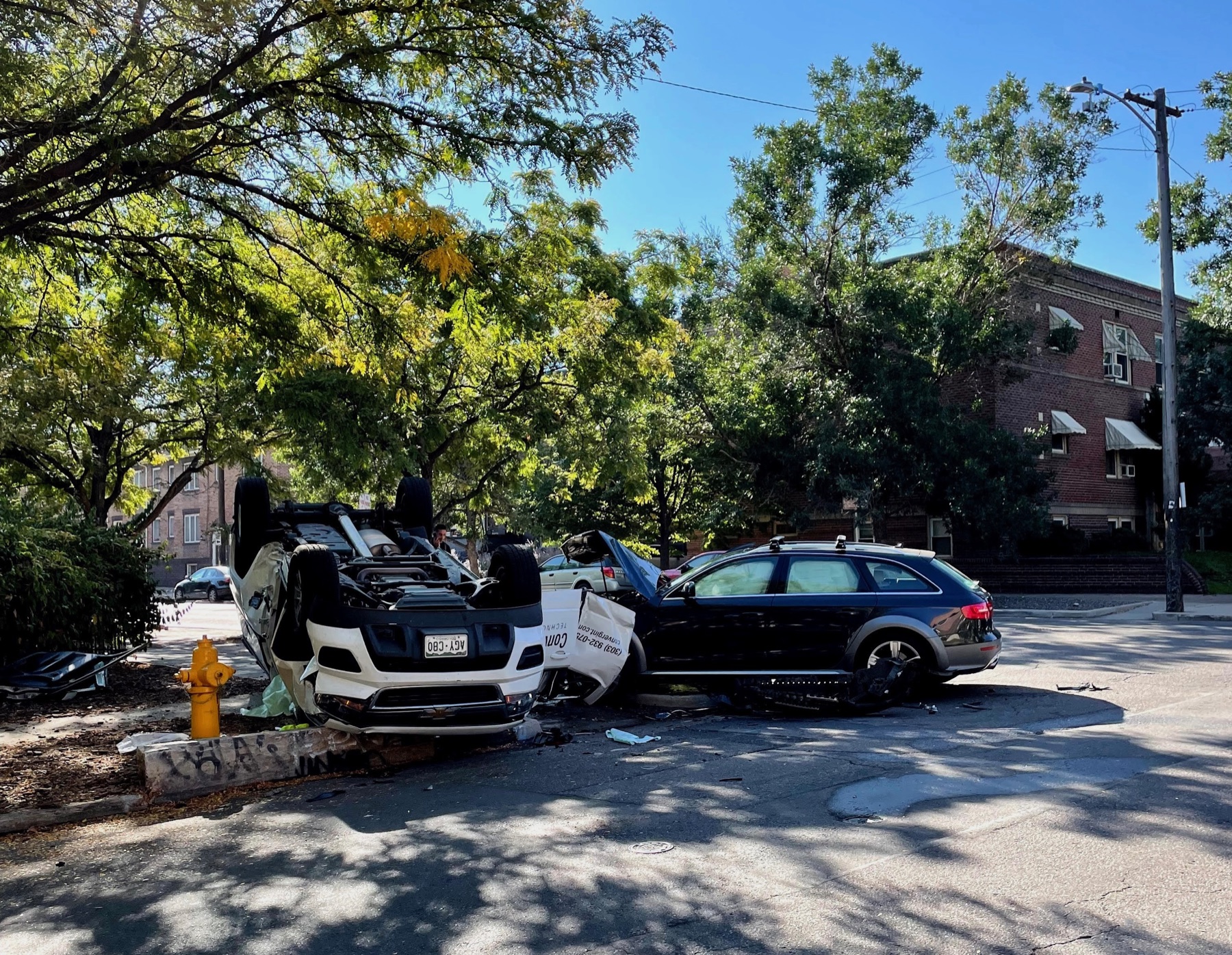 An overturned vehicle and a damaged parked car at an East Avenue intersection